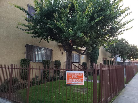A sign is posted on a fence in front of a building.