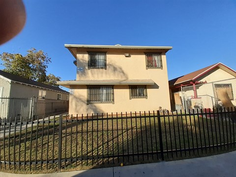 A two-story house with a black fence in front.