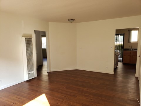 A large empty room with wood flooring and white walls.