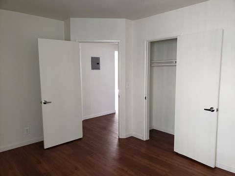 A room with white walls and wood floors with three doors.