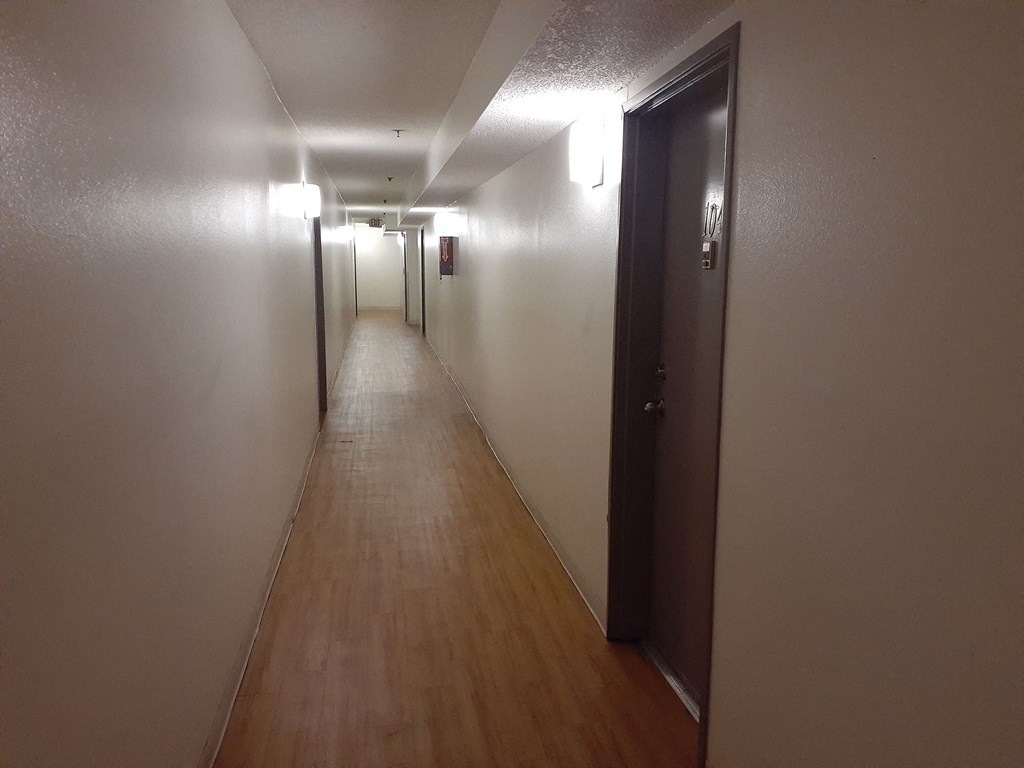 a long hallway with wood floors and white walls and a door