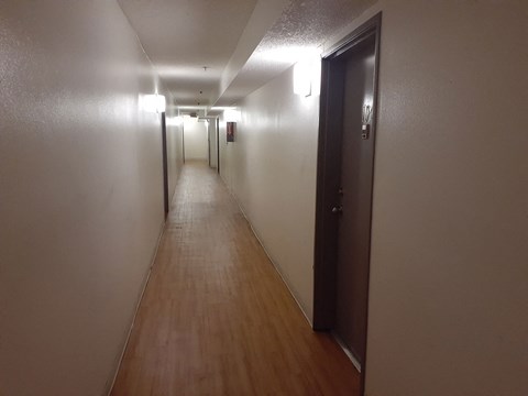 a long hallway with wood floors and white walls and a door
