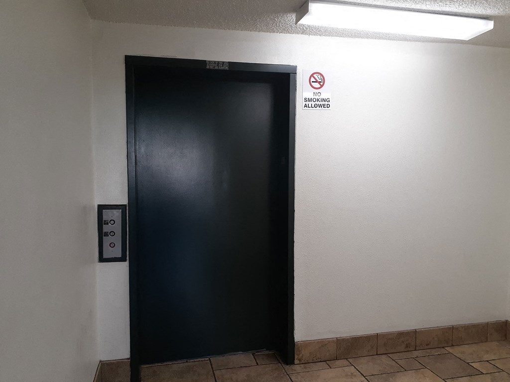 a black elevator door with a no smoking sign on it