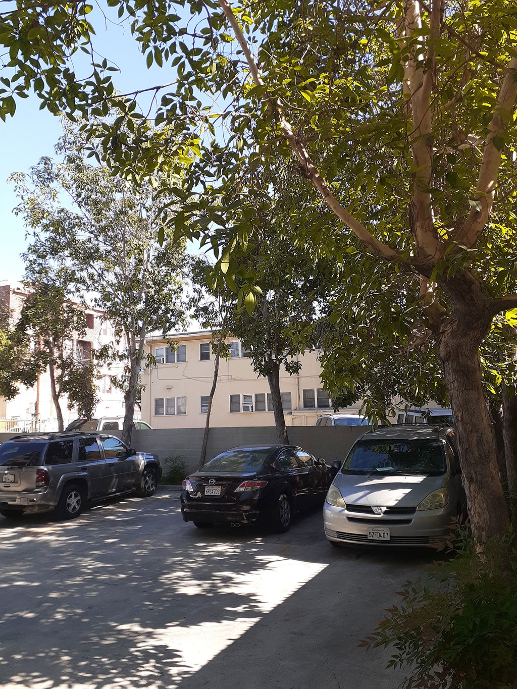 a parking lot with cars and trees in front of a building