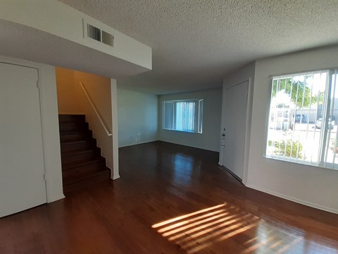 A room with wooden floors and a staircase leading to another floor.