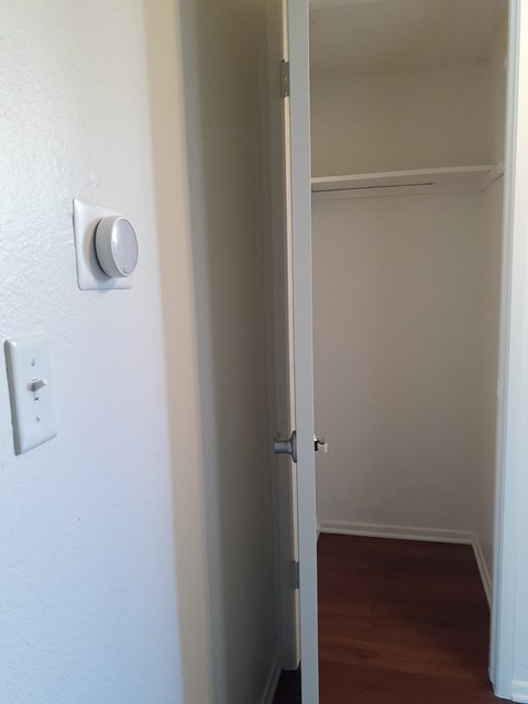 A white door with a silver handle and a white wall with a switch.