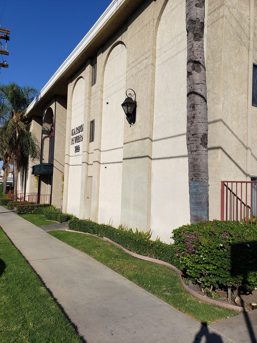 the side of a building with a sidewalk and palm tree