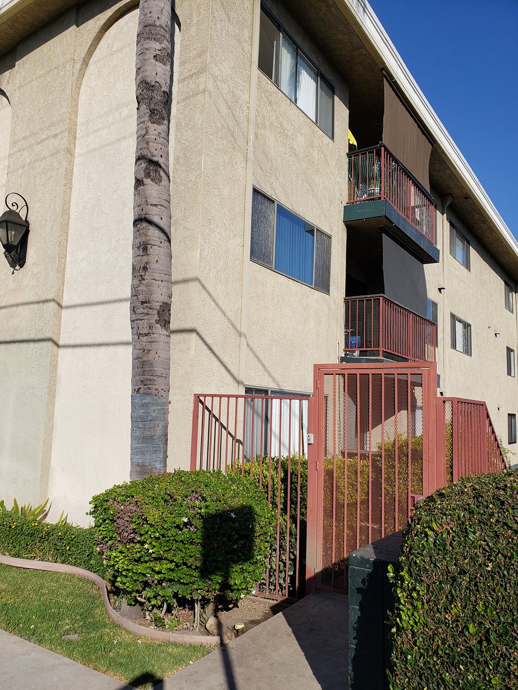 an exterior view of an apartment building with a red gate