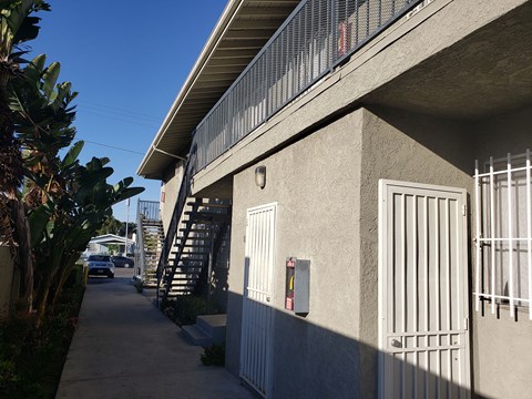 A concrete building with a metal gate and a staircase leading to the second floor.