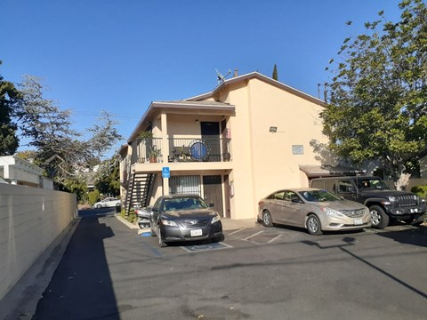 A car is parked in front of a building with a blue sign on it.