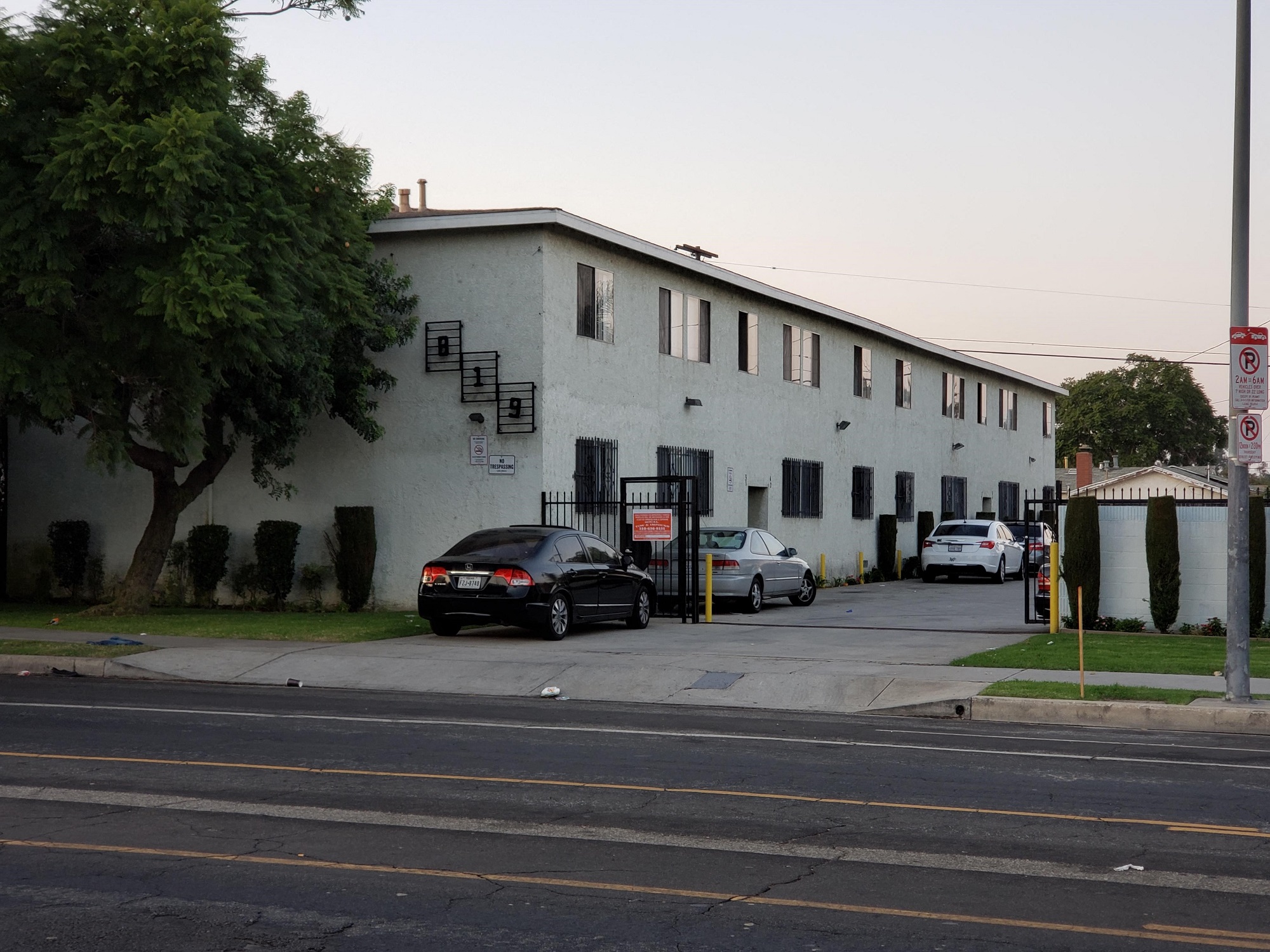 A black car is parked in front of a white building.