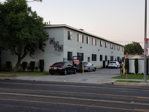 A black car is parked in front of a white building.