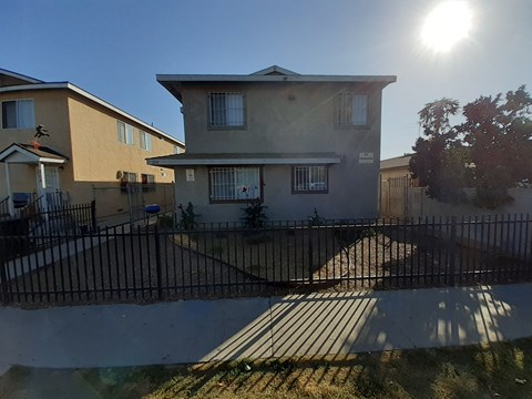 A sunny day in a residential area with houses and a black fence.