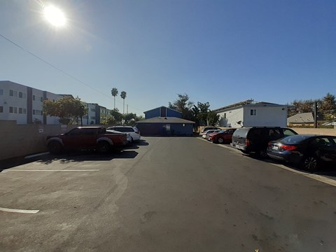 A parking lot with cars and buildings under a clear sky.