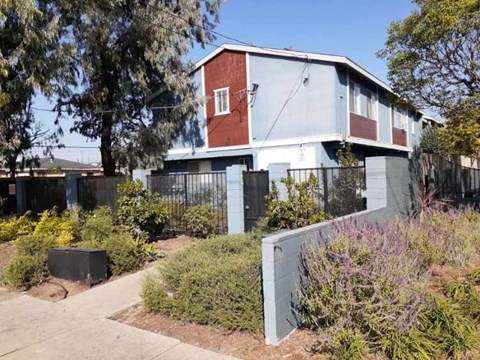 A red and white building with a blue fence and bushes in front.