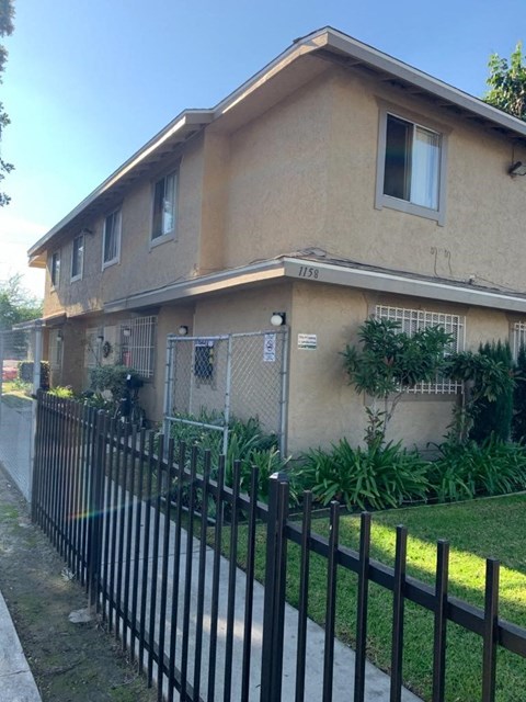 A beige house with a black fence in front.