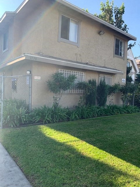 A house with a fence and green plants in front.
