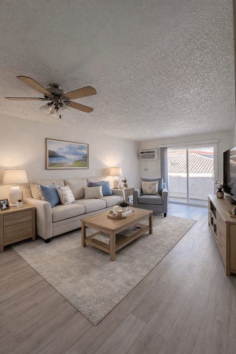 A living room with a couch, coffee table, and a ceiling fan.