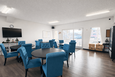 A conference room with blue chairs and a television on the wall.
