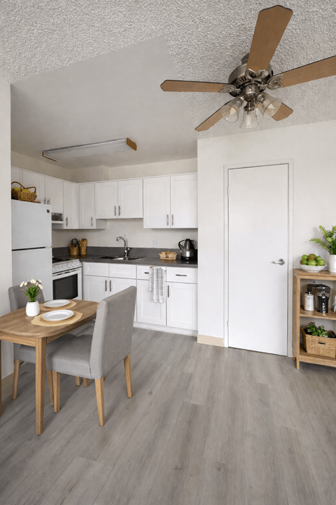 A kitchen with a table and chairs in front of a refrigerator.
