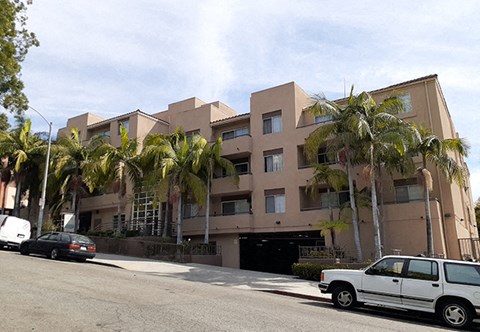 a building with palm trees and cars parked in front of it