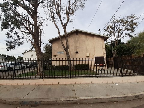 A small building with the number 2927 on it is surrounded by a black fence.