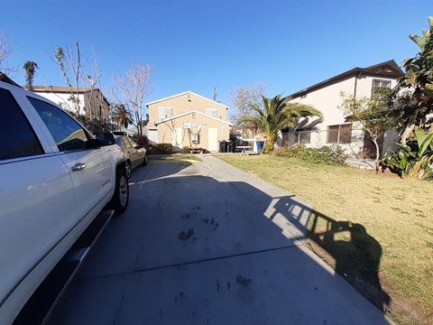 A white car is parked on a driveway in front of a house.