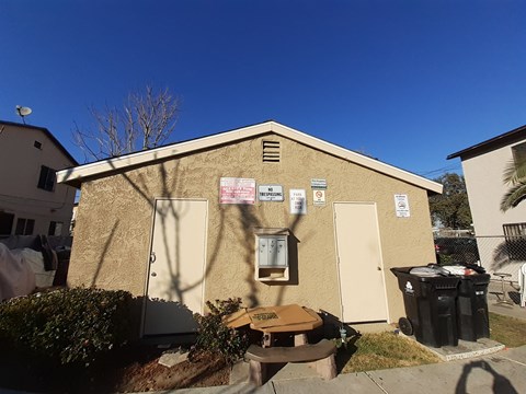 A small building with a brown door and a brown bench in front of it.