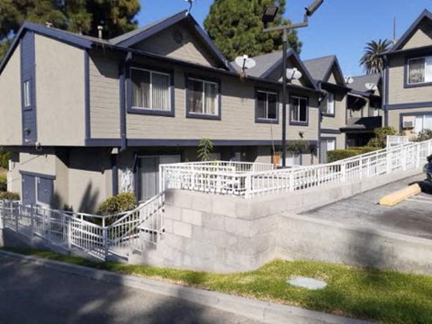 A row of houses with a white fence in front.