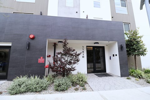 A modern building with a grey facade and a tree in front.