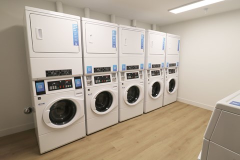 A row of white front loading washing machines in a laundromat.