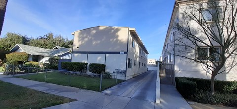 A long, narrow road with a sidewalk on one side and a fence on the other.