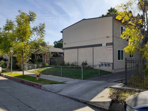 A building with a fence and a tree with yellow leaves in front of it.