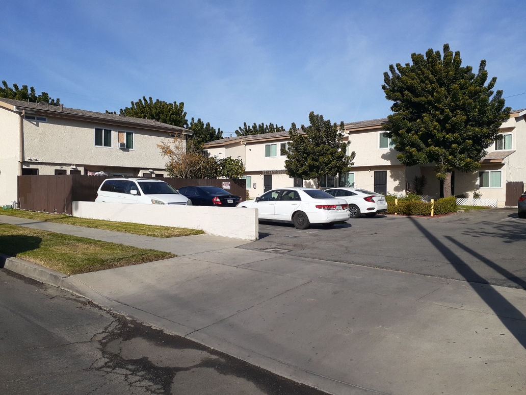 A white car is parked in front of a house.