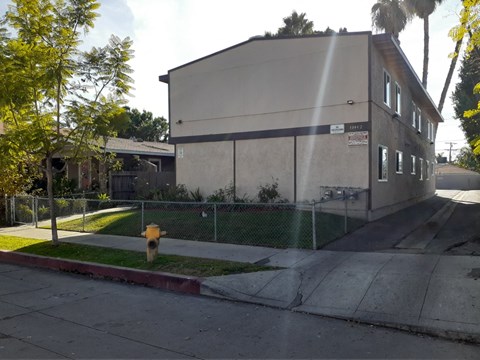 A building with a fence and a yellow fire hydrant in front of it.