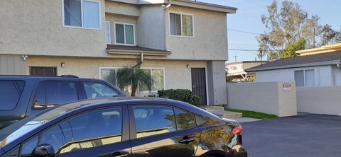 A black car is parked in front of a two-story house.