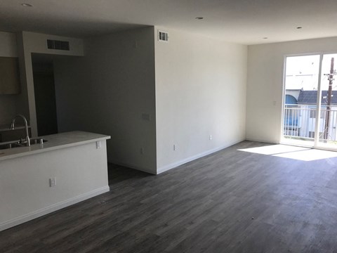A large empty room with a kitchen area to the left.