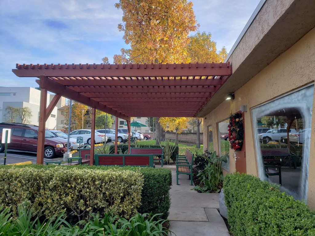 a covered patio with benches in front of a building