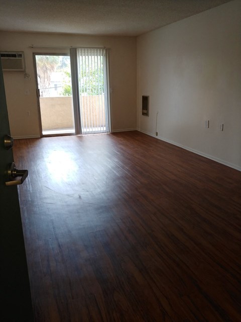 an empty living room with wooden floors and a sliding glass door