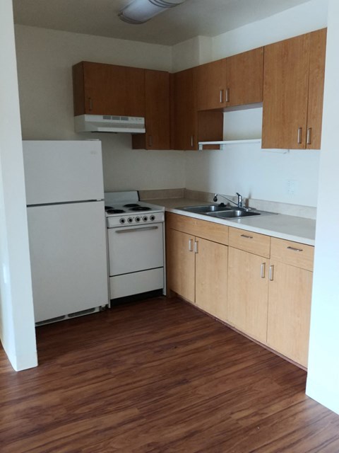 an empty kitchen with white appliances and wooden cabinets