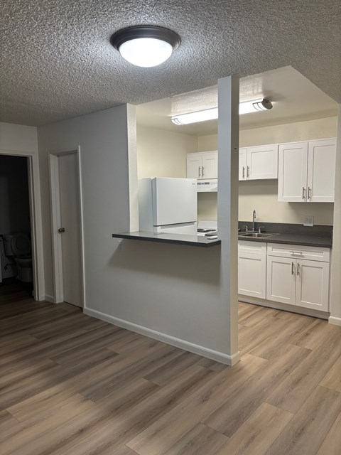 A kitchen with white cabinets and a refrigerator.