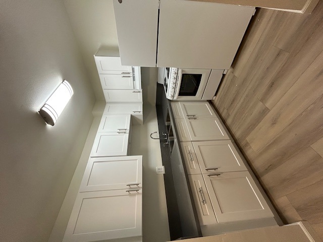 A kitchen with white cabinets and a wooden floor.