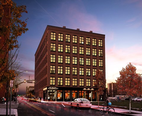 A large building with many windows is lit up at dusk.