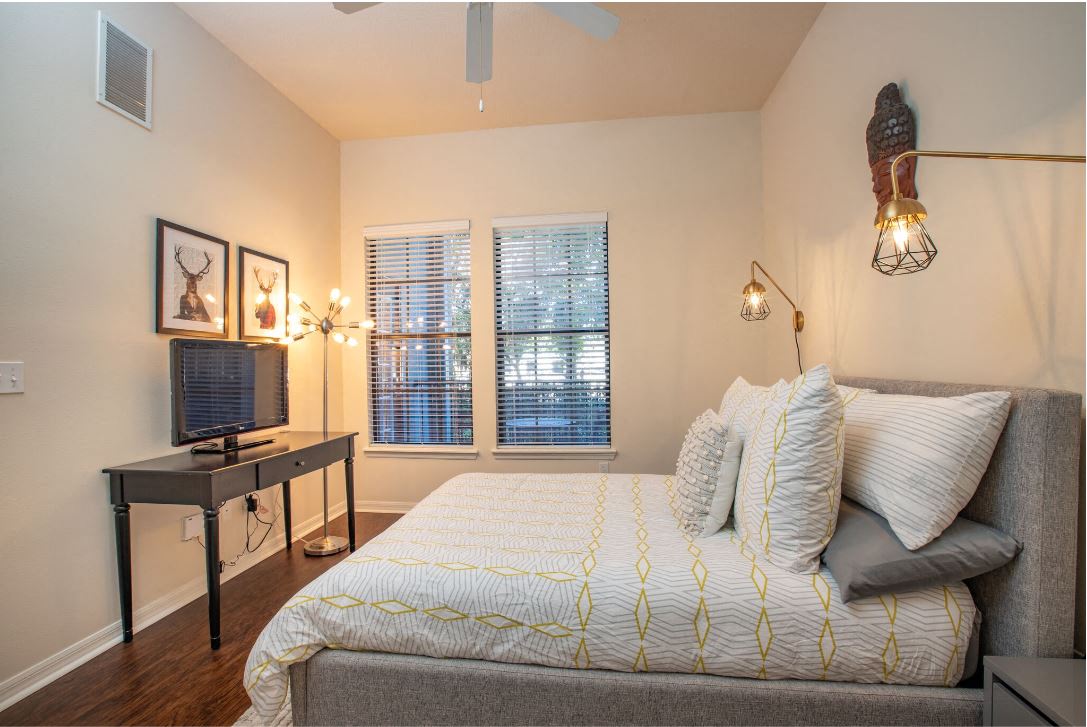 2nd bedroom from bathroom angle. TV on top of desk against the left wall at The Bartram Apartments in Gainesville, FL 32608