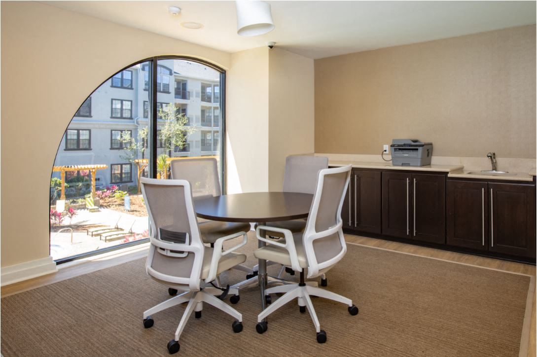 Round table with 4 computer desk chairs and printer located on top of counter. Located on the 2nd floor of Clubhouse at The Bartram Apartments in Gainesville, FL 32608