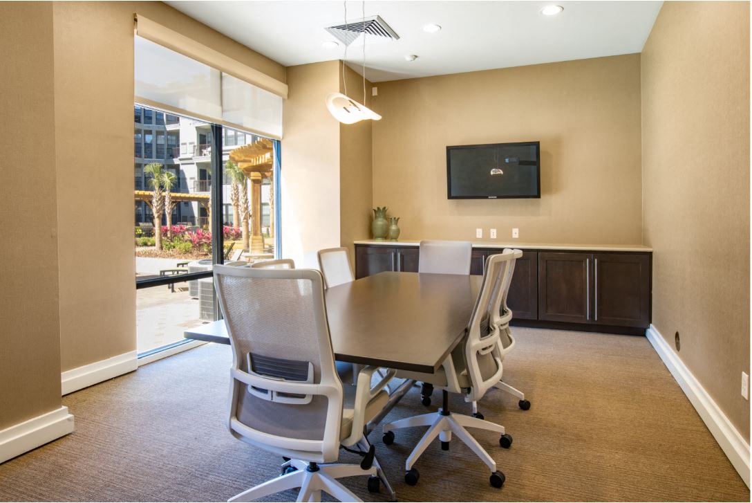 Business center with conference table with chairs and TV & printer at The Bartram Apartments in Gainesville, FL 32608