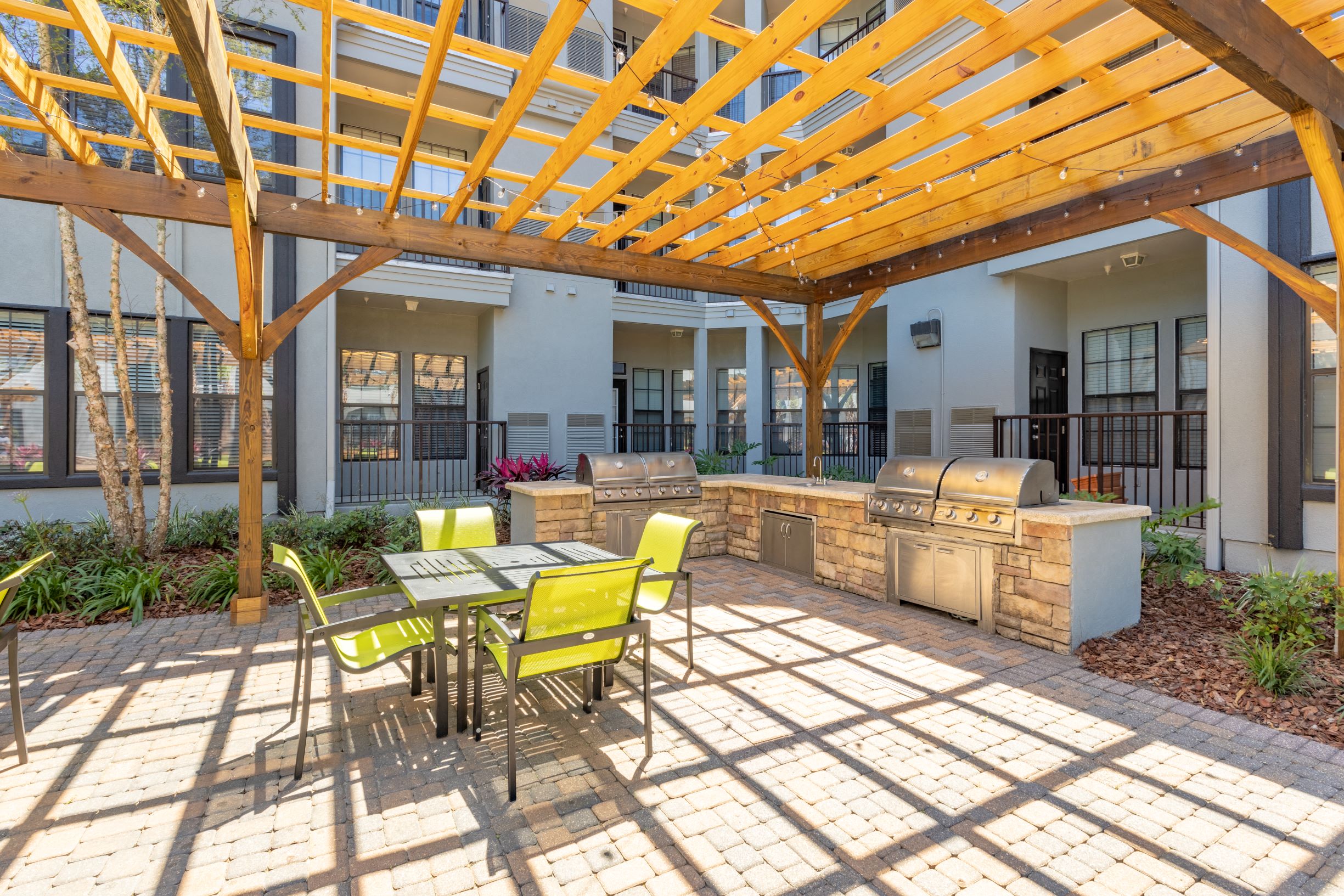 Courtyard pool BBQ Grill area with outdoor seating at The Bartram Apartments in Gainesville, FL 32608