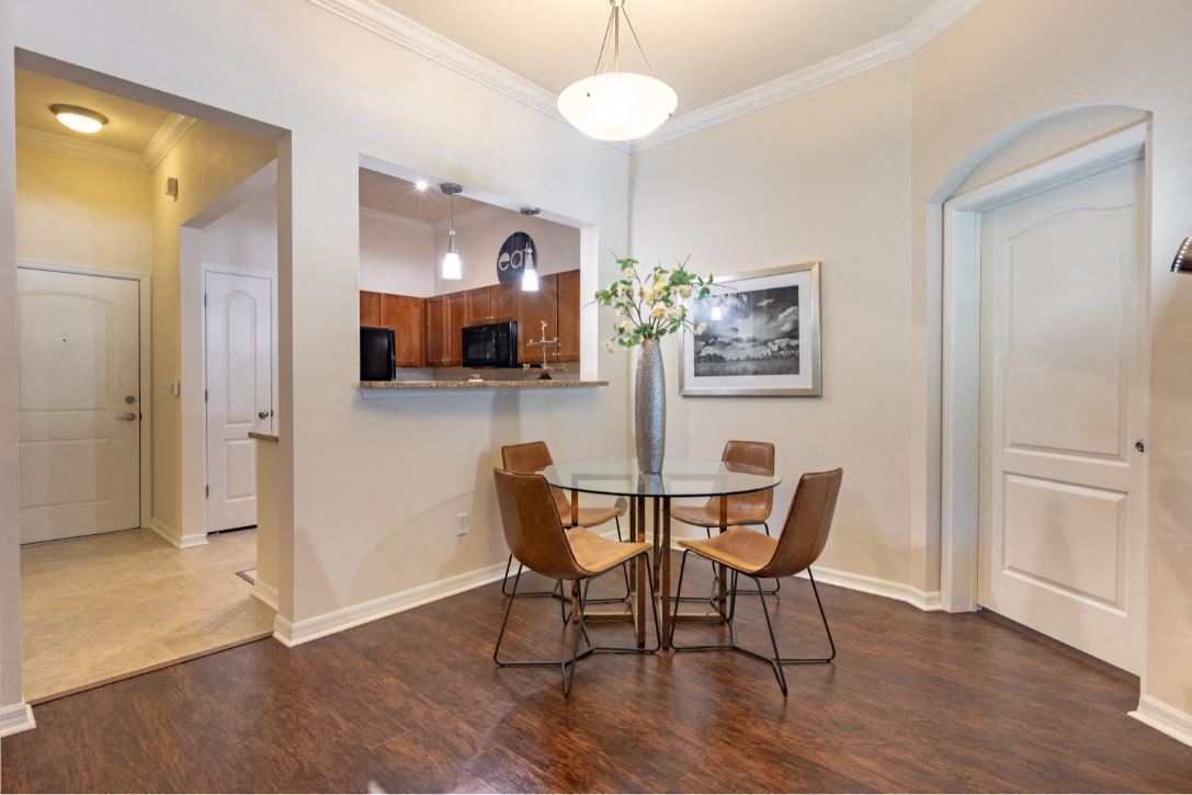Dining room area located in front of kitchen bar. 4 seater round glass table pictured at The Bartram Apartments in Gainesville, FL 32608