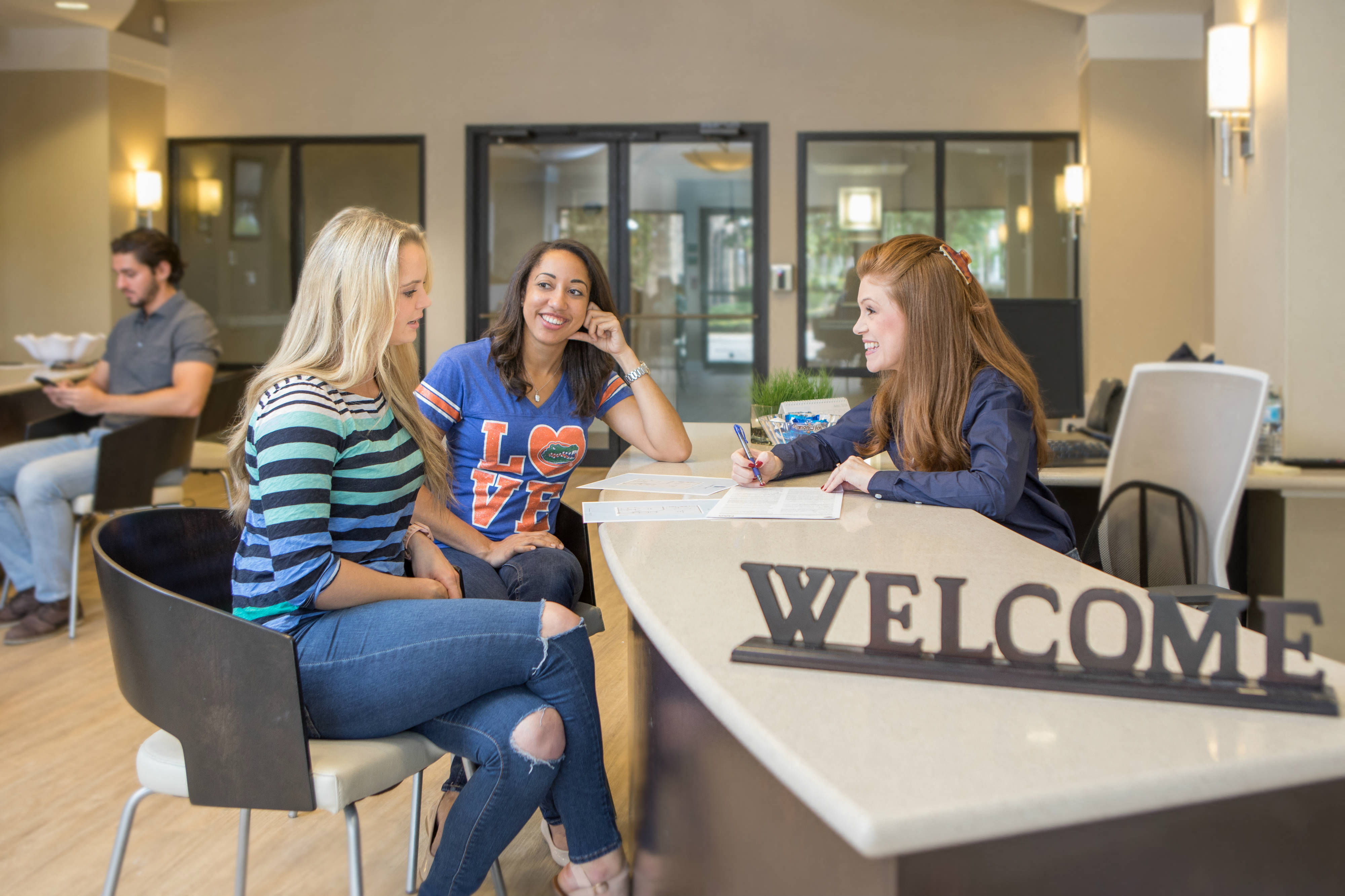 People signing a lease in office lobby with leasing agent sitting at the desk at The Bartram Apartments in Gainesville, FL 32608