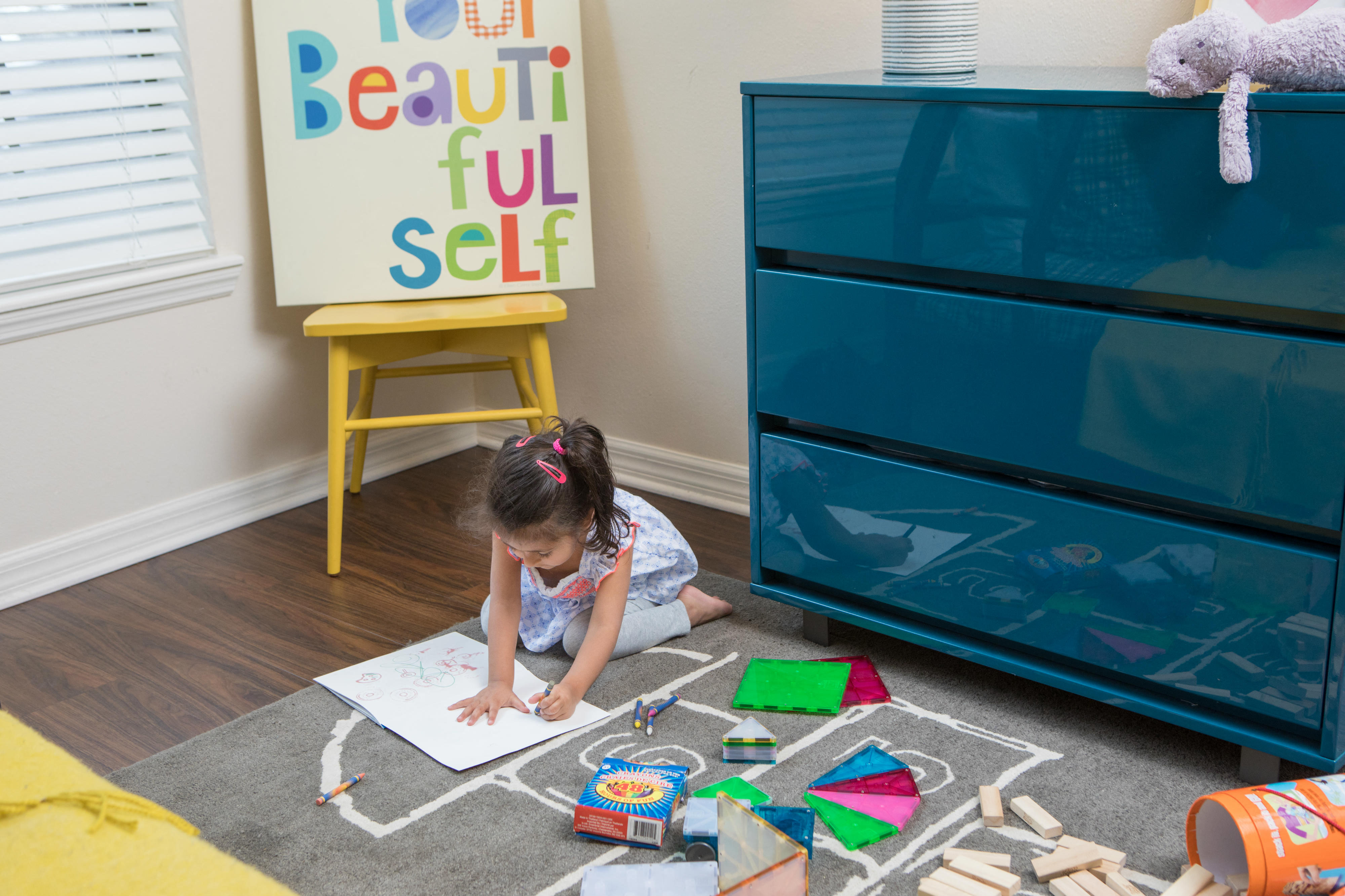 Toddler aged girl sitting on the bedroom floor coloring in a coloring book at The Bartram Apartments in Gainesville, FL 32608
